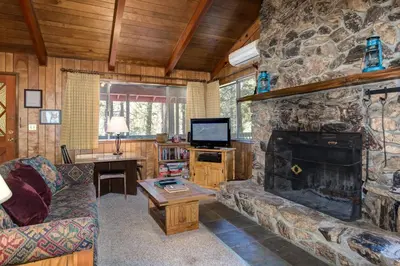 a living room with a stone fireplace and a television at Robin's Nest in Wawona