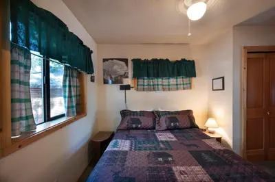 a bedroom with a bed and a window with green curtains at Wawona Cabin in Wawona