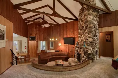 a living room with a couch and a stone fireplace at Villarreal Retreat in Wawona