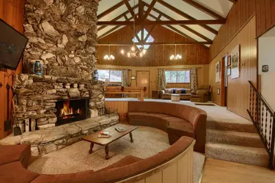 a living room with a fireplace and a stone wall at Villarreal Retreat in Wawona