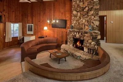 a living room with a couch and a stone fireplace at Villarreal Retreat in Wawona