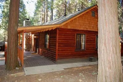 a log cabin with a deck in the woods at Deer Den in Wawona