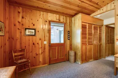 a room with wooden walls and a door and a chair at Quail Meadow in Wawona