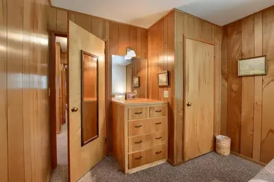 a bathroom with wooden walls and a sink and a mirror at Quail Meadow in Wawona