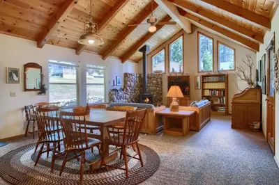 a living room with wooden ceilings and a table and chairs at Quail Meadow in Wawona