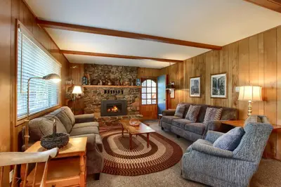 a living room with couches and a stone fireplace at Quail Meadow in Wawona