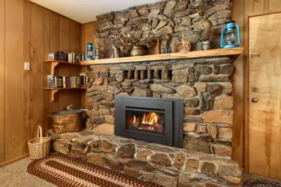 a stone wall with a fireplace in a room at Quail Meadow in Wawona