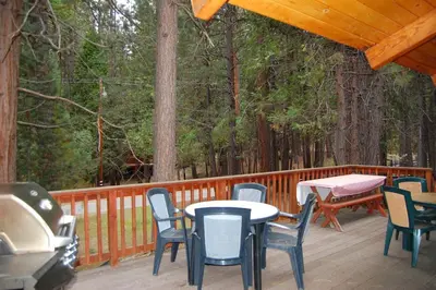 a deck with tables and chairs and a grill at Dunning's Retreat in Wawona