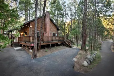 a log cabin in the woods with a porch at Grandma's Cabin in Wawona
