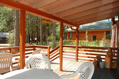 a wooden deck with a table and chairs on it at Cubby's Den in Wawona
