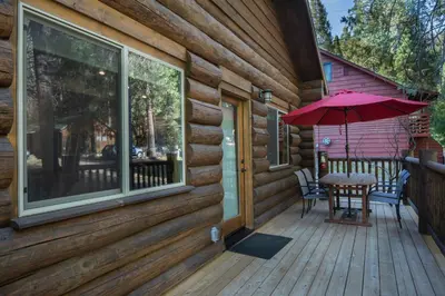 a wooden deck with a table and an umbrella at The Mini Cabin in Wawona