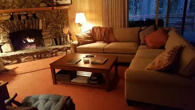 a living room with a couch and a table with a fireplace at River Song in Wawona