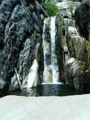 a waterfall on the side of a rocky mountain at River Song in Wawona