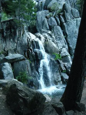 a waterfall on the side of a rocky mountain at River Song in Wawona