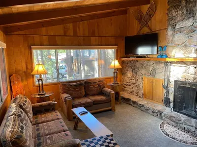 a living room with a couch and a stone fireplace at Cutter's Edge in Wawona