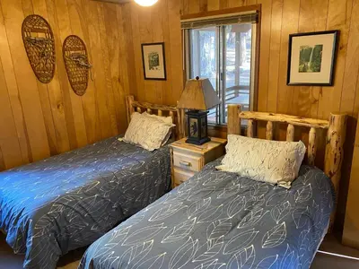 two beds in a room with wood paneled walls at Cutter's Edge in Wawona