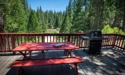 a wooden deck with a picnic table and a grill at Lockwood Lodge in Wawona