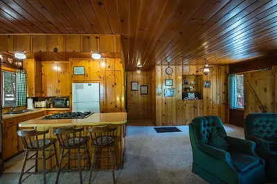 a kitchen with wooden walls and a kitchen island with bar stools at Lockwood Lodge in Wawona
