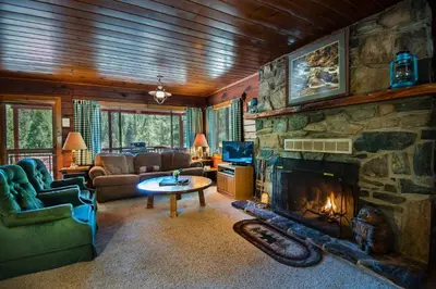 a large living room with a stone fireplace at Lockwood Lodge in Wawona
