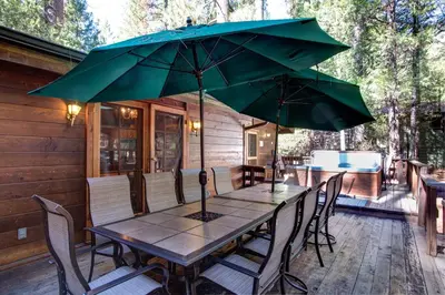 a wooden table with two large umbrellas on a patio at Cedar Chalet in Wawona