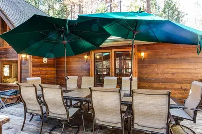 a patio with tables and chairs and umbrellas at Cedar Chalet in Wawona