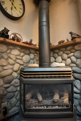 a stone fireplace with a clock on a wall at Rosenberg's Creekside Cabin in Wawona