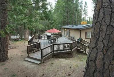 a large wooden deck with a picnic table and a house at Rosenberg's Creekside Cabin in Wawona