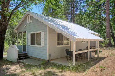 a tiny house with a porch and a white roof at Edna's Hearts Desire in Wawona