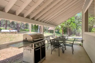 a outdoor kitchen with a grill and a table with chairs at Edna's Hearts Desire in Wawona