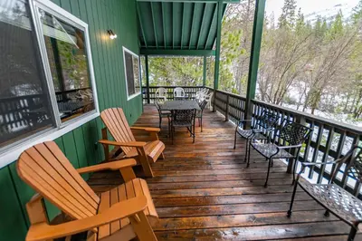 a wooden porch with chairs and tables and windows at Grant's Camp in Wawona