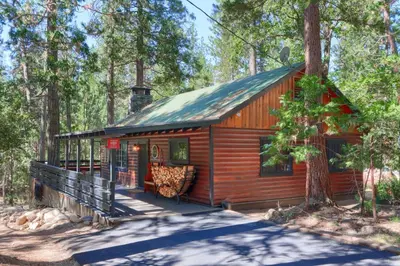 a log cabin in the woods with a porch at The Overlook in Wawona