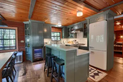 a kitchen with green cabinets and a island with bar stools at The Overlook in Wawona