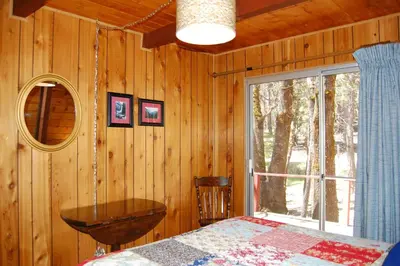 a bedroom with a bed and a mirror and a window at Manzanita Lodge in Wawona