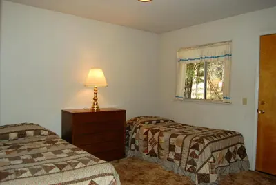 a bedroom with two beds and a lamp and a window at Altitude Adjustment in Wawona