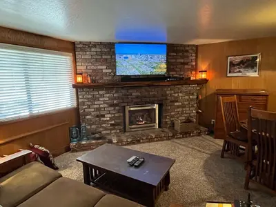 a living room with a fireplace with a flat screen tv at The Tree House II in Wawona