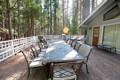 a wooden deck with a long table and chairs at The Tree House II in Wawona