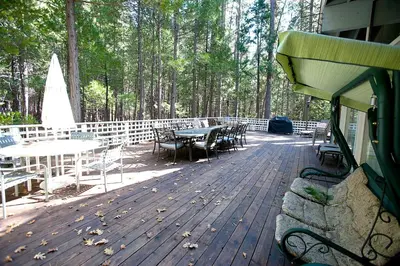 a wooden deck with tables and chairs and trees at The Tree House II in Wawona