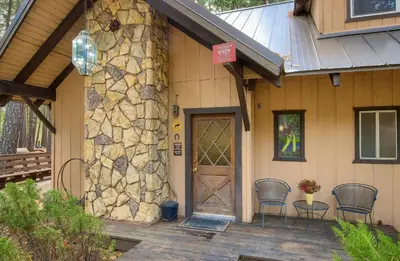 a front door of a house with chairs and a stone wall at Spindler's Chalet in Wawona