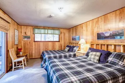 two beds in a room with wood paneling at Soots-Me in Wawona