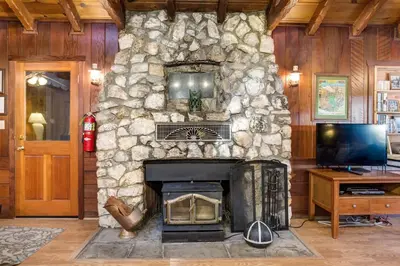 a stone fireplace in a living room with a television at Soots-Me in Wawona