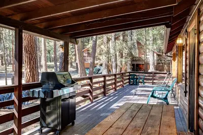 a screened in porch with a grill and chairs on a deck at Mia Mora in Wawona