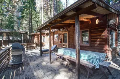 a log cabin with a picnic table on a deck at Creekside Cabin in Wawona