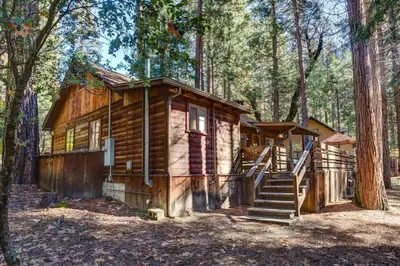 a log cabin in the woods with a staircase at Creekside Cabin in Wawona