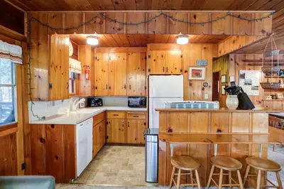 a kitchen with wooden cabinets and a white refrigerator at Creekside Cabin in Wawona