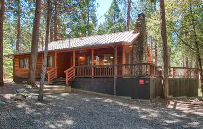 a log cabin in the woods with a porch at Deer Creek in Wawona