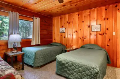 two beds in a room with wooden walls at Deer Creek in Wawona