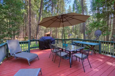 a deck with a table and chairs and an umbrella at The Williams Cabin in Wawona