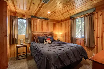 a bedroom with a large bed in a wooden room at The Williams Cabin in Wawona