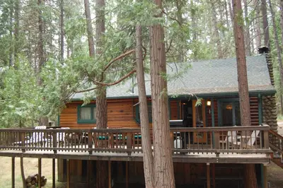 a log cabin with a deck in the woods at Hansen Cabin in Wawona