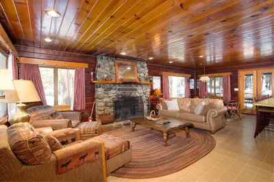 a living room with couches and a stone fireplace at Hansen Cabin in Wawona